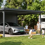 Ein moderner Carport bietet Schatten für ein Auto und ein Wohnmobil, während eine Familie einen sonnigen Tag im Garten genießt.